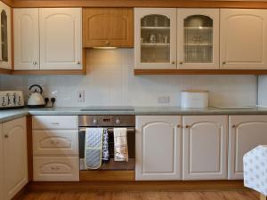 a kitchen with white cabinets and a stove top oven at Cotton Shore in Inverallochy