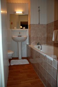 La salle de bains est pourvue d'un lavabo, d'une baignoire et de toilettes. dans l'établissement Hotel De France, à Pontorson