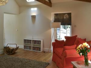 un soggiorno con divano rosso e libreria di The Stables a Berwick Hill