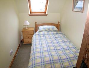 Habitación pequeña con cama y mesita de noche en The Cottage, en Ankerville
