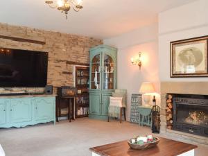 a living room with a tv and a fireplace at Cross Cottage in Haworth