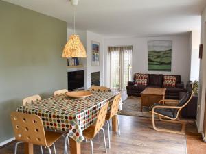 een woonkamer met een tafel met stoelen en een bank bij Mussel Cottage in Middleton-on-Sea
