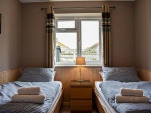 two beds in a room with a window at Mussel Cottage in Middleton-on-Sea