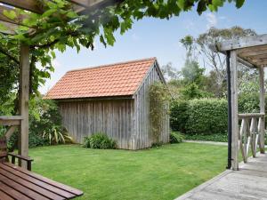 a garden with a wooden shed with a green lawn at Mussel Cottage in Middleton-on-Sea