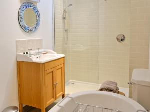 a bathroom with a bath tub and a sink and a bath tub at The Barn in Greystoke