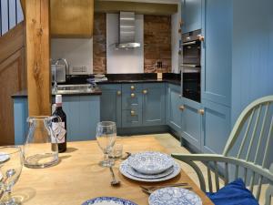 a blue kitchen with a wooden table with plates and glasses at The Barn in Greystoke