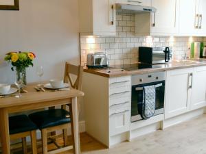 a kitchen with white cabinets and a wooden table at Holly Bank Cottage in Settle