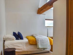a room with a bed with blue and yellow pillows at Grove Barn in Carisbrooke
