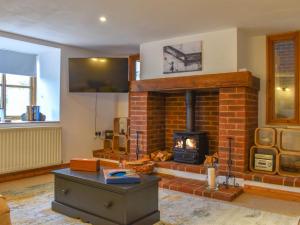 a living room with a brick fireplace with a stove at Grove Barn in Carisbrooke