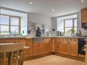 a kitchen with wooden cabinets and a sink and windows at Grove Barn in Carisbrooke