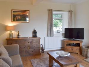 a living room with a couch and a tv at Ling Farm Cottage in Holmewood