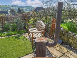 a garden with two wooden chairs and a pole at Grove Barn in Carisbrooke