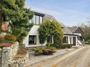 a white house with a tree and a street at Forge Mill Cottage in Dalbeattie