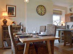 a dining room table with chairs and a clock on the wall at Ling Farm Cottage in Holmewood