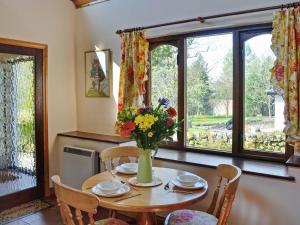a dining room table with a vase of flowers on it at Forge Mill Cottage in Dalbeattie