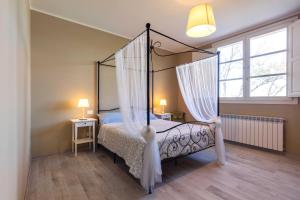 - une chambre avec un lit à baldaquin et des rideaux blancs dans l'établissement The Olive Grove in Tuscany, à Toiano