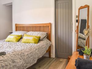 a bedroom with a bed with yellow pillows and a mirror at Redmonds Retreat in Chinley