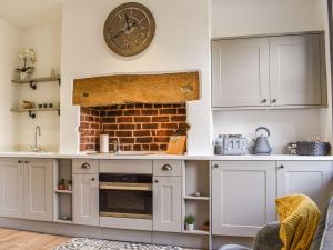a kitchen with white cabinets and a clock on the wall at Redmonds Retreat in Chinley