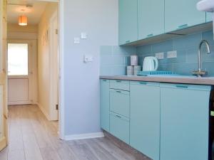 a blue kitchen with blue cabinets and a sink at Valley View in Morwenstow