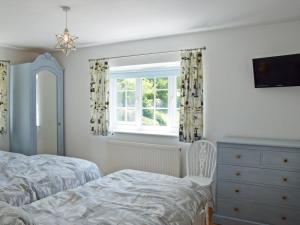 a bedroom with a bed and a dresser and a window at Woodbrook Cottage in Bridport