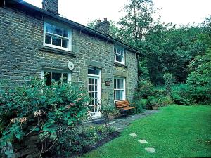 een stenen huis met een bank in de tuin bij Drum And Monkey Cottage in Chapel en le Frith