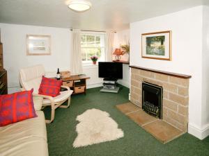a living room with a fireplace and a tv at Drum And Monkey Cottage in Chapel en le Frith