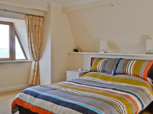 a bedroom with a bed with a colorful striped blanket at Waterside in Tighnabruaich