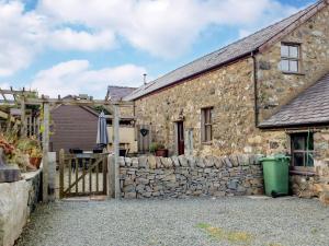 a stone house with a stone wall and a fence at Clogwyn Bach in Trevor