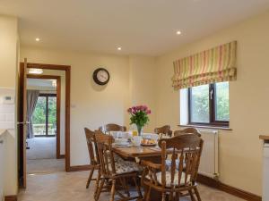 a dining room with a table and chairs and a clock at Coed Tir in Gladestry