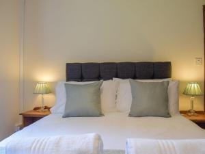 a bedroom with a large white bed with two lamps at Coed Tir in Gladestry