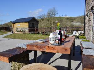 una mesa de madera con una botella de vino. en Maes Merlin, en Llanddeusant