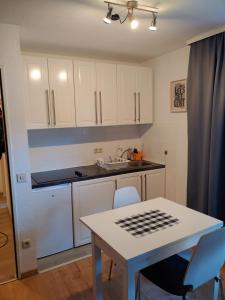 una cocina con armarios blancos y una mesa con sillas. en Ferienwohnung Alpina Inzell en Inzell