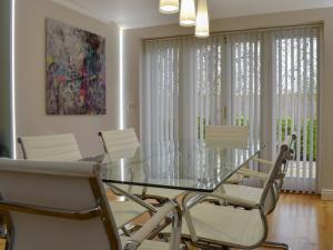 uma sala de jantar com uma mesa de vidro e cadeiras brancas em Hollies Cottage 15 - Ukc4538 em Martock