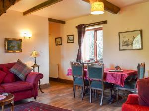 Acorn Barn في Foggathorpe: غرفة معيشة مع طاولة وأريكة حمراء