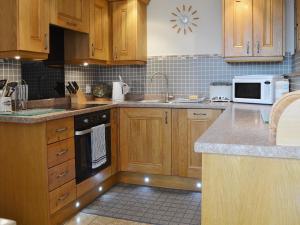 a kitchen with wooden cabinets and a stove top oven at The Carriage House in Watermillock