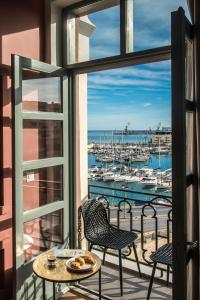 balcone con tavolo, sedie e vista su un porto turistico. di The Blossom Collection in Heraklion City Center a Heraklion