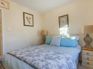 a bedroom with a bed with blue pillows on it at Wrens Nest in Moreton in Marsh