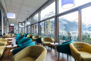 a waiting room with chairs and tables and windows at Hotel Terrace in Engelberg