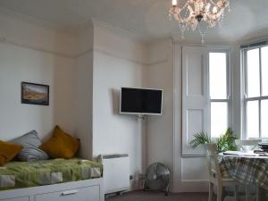 a living room with a couch and a tv on the wall at Flat 2 Beachview - Ukc4220 in Lowestoft