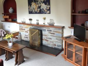 sala de estar con chimenea de ladrillo y TV en The Gazebo, en Marazion