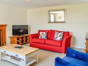 - un salon avec un canapé rouge et une télévision dans l'établissement Mullhill, à Ardwell