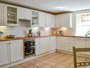 - une cuisine blanche avec des placards blancs et une table dans l'établissement Mullhill, à Ardwell