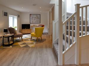 a living room with a staircase and a yellow chair at Bonnie Cottage - Uk40057 in Aberfeldy