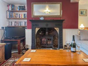 a living room with a fireplace and a table with wine glasses at Mays Cottage in Melbury Abbas