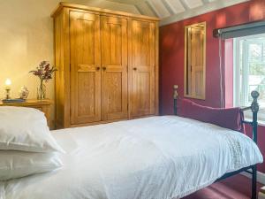 a bedroom with a white bed and a wooden cabinet at Mays Cottage in Melbury Abbas