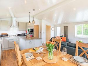 a kitchen and living room with a wooden table and a dining room at Viburnum Lodge in Willington