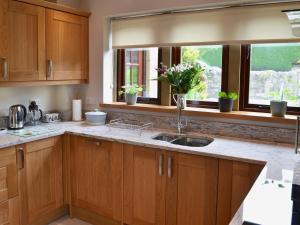 una cucina con armadi in legno, lavandino e due finestre di Stoneleigh a Baslow