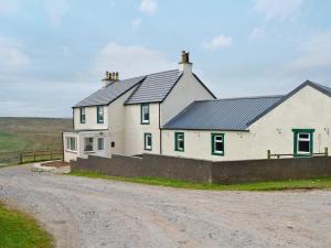 a white house with black roof on a dirt road at High Ranachan in Campbeltown