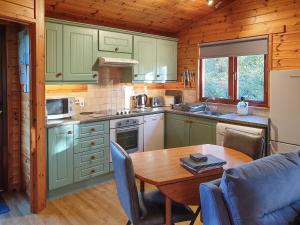 a kitchen with green cabinets and a table in a room at Burnside Alderwood in Garboldisham
