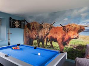 a mural of three cows on a wall with a pool table at High Ranachan in Campbeltown